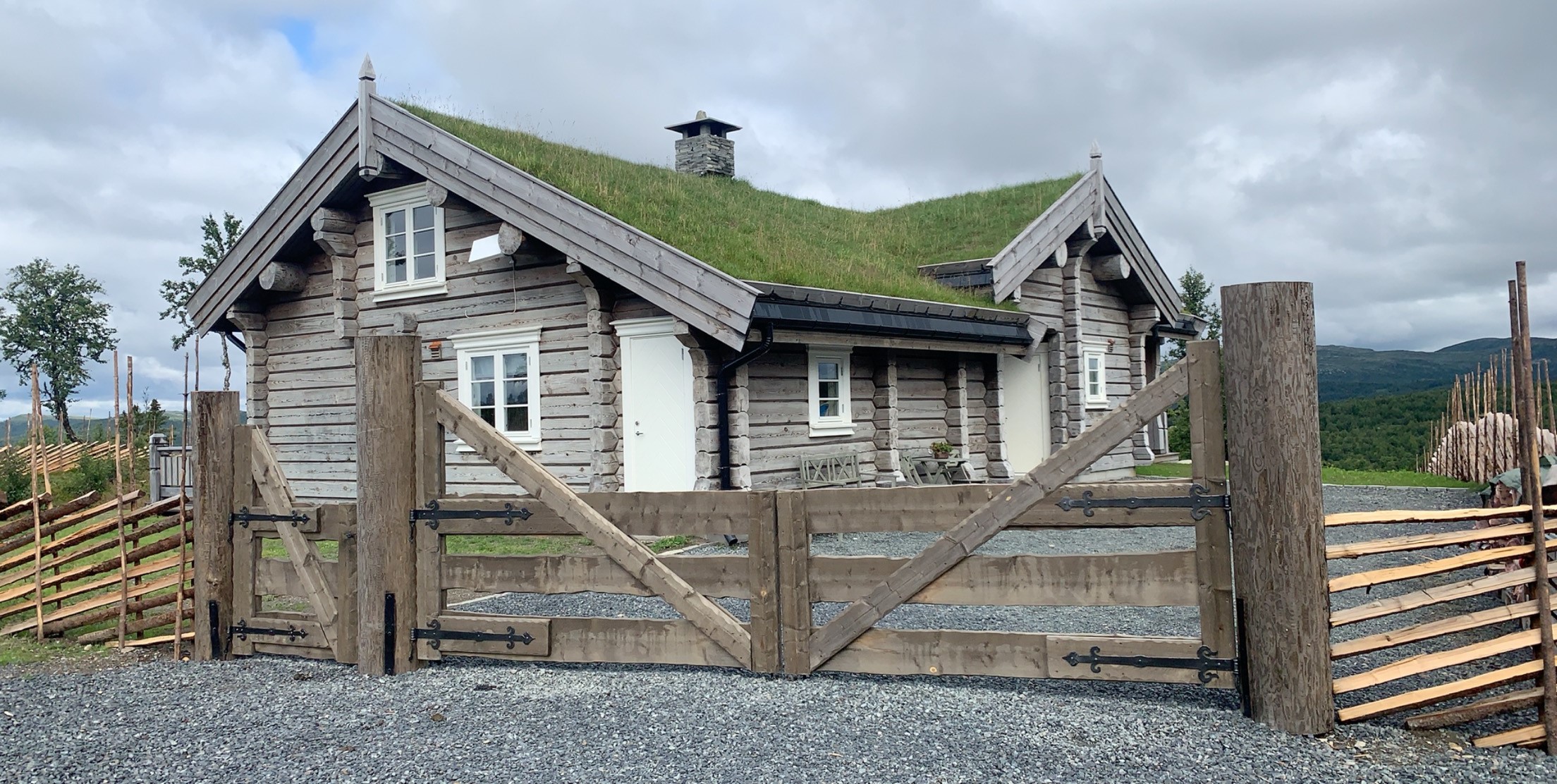 Stor portløsning med gangport ved siden, hengsler i smijern. Stolper og port behandlet med jernvitrol.